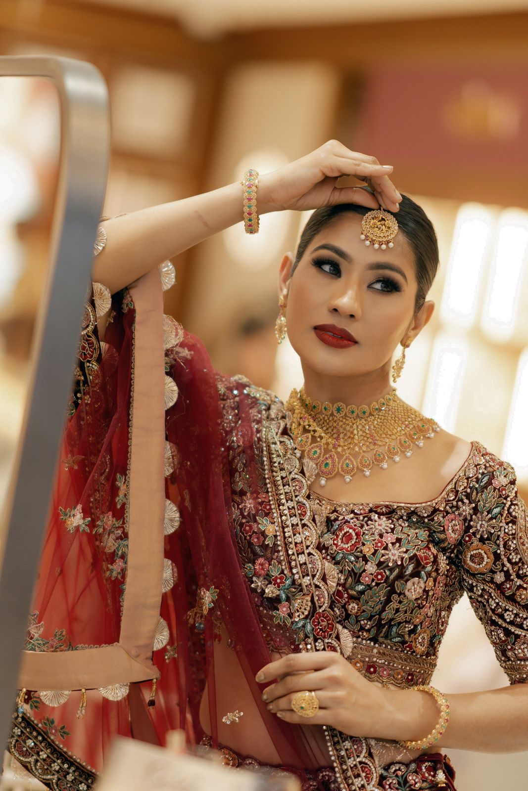 Model in bridal jewellery and a maroon lehenga